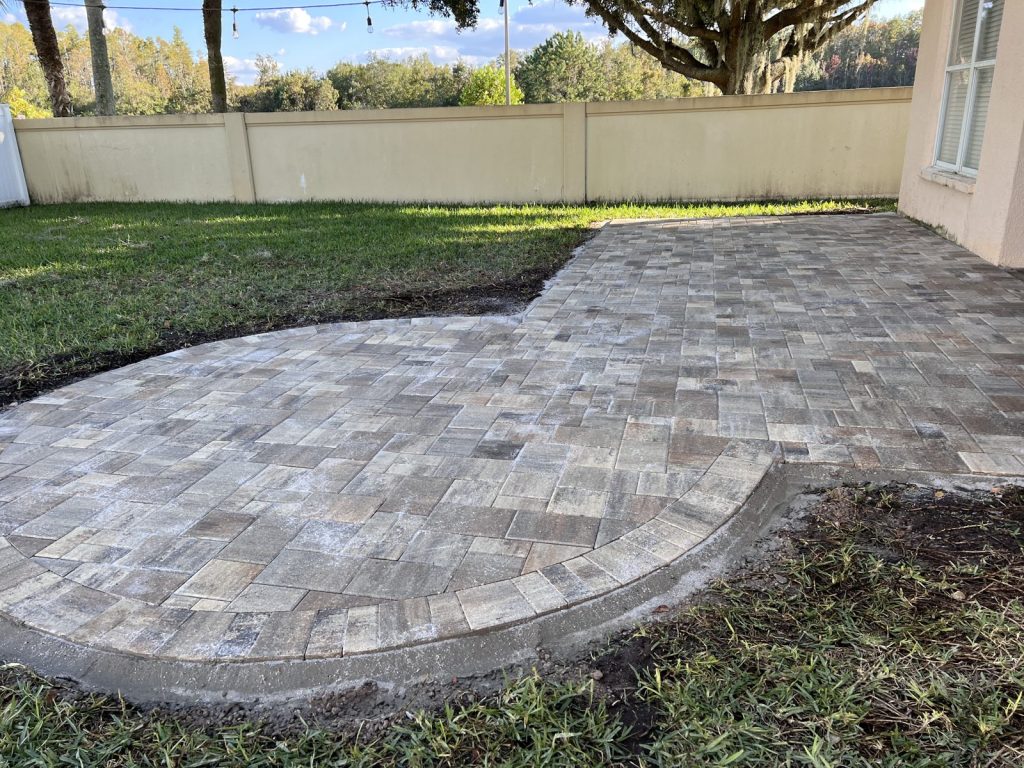 Newly installed brick paver patio with a curved border, before its first seal